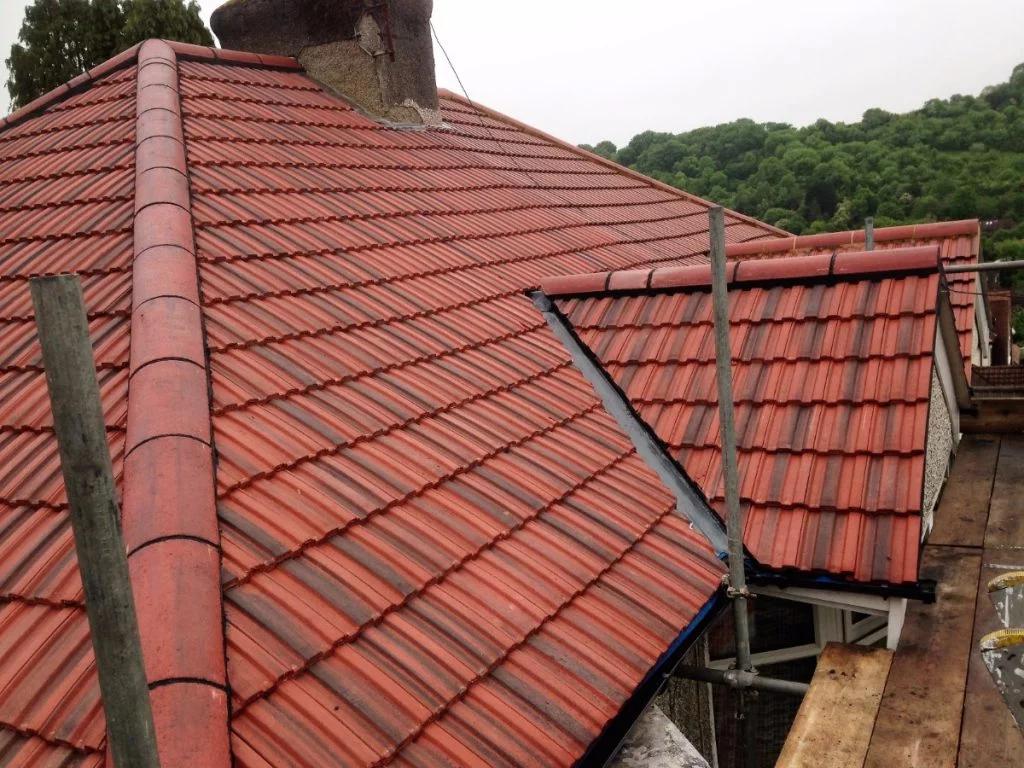 Newly tiled red pitched roof and chimney with scaffolding in view