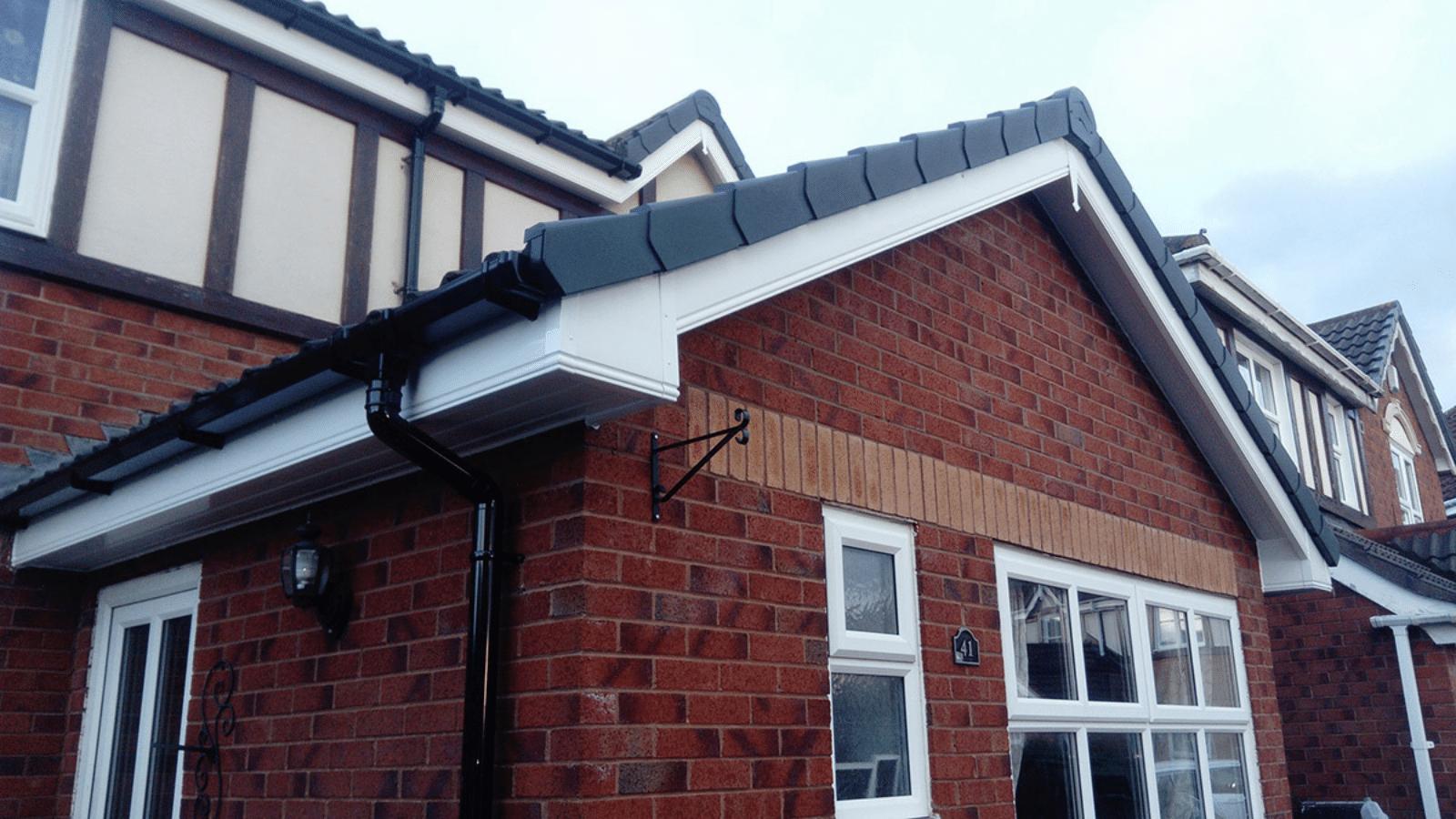 Newly fitted black guttering and fascia on a modern brick home
