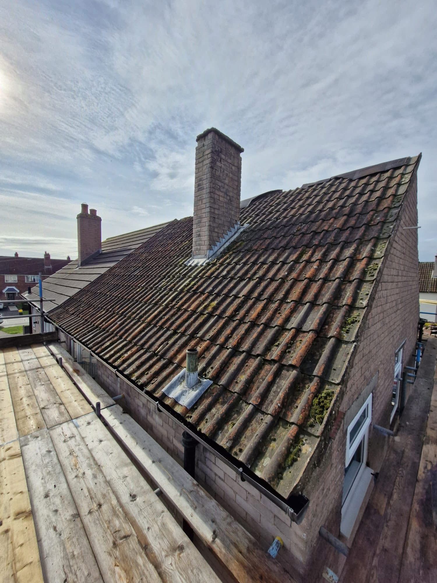 Aged red pantile roof with moss and chimney prior to repair work