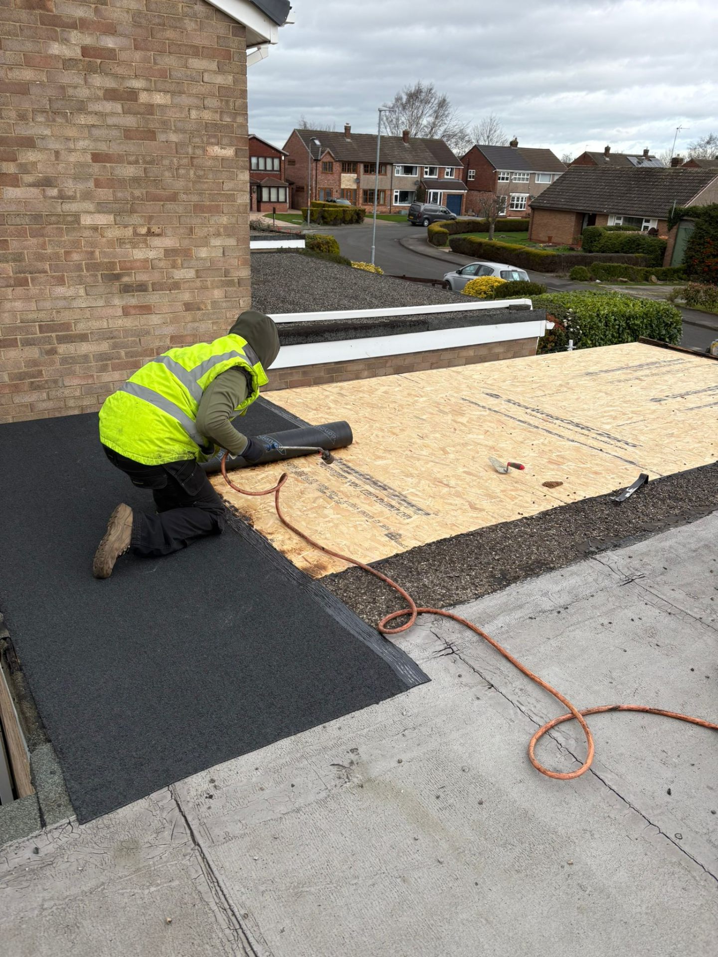 Roofer installing a new flat roof on a residential building