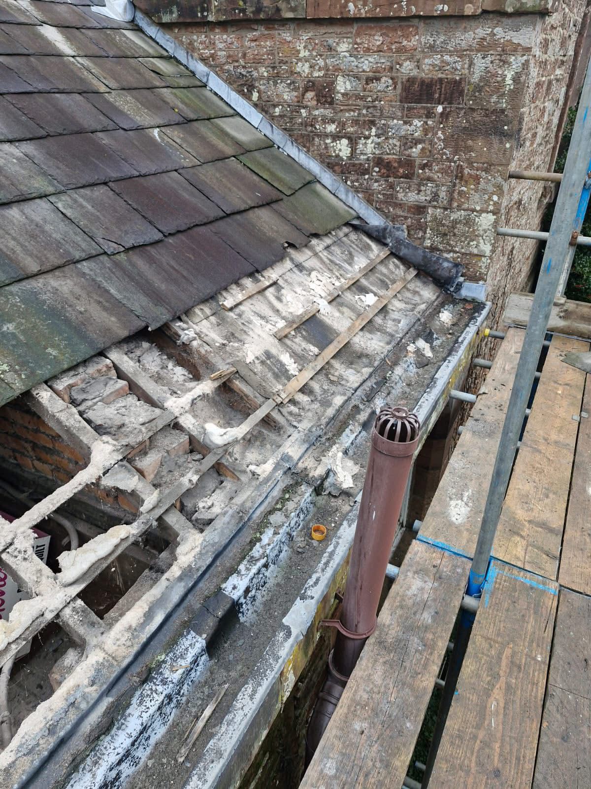 Steep slate roof with missing tiles exposing battens during renewal